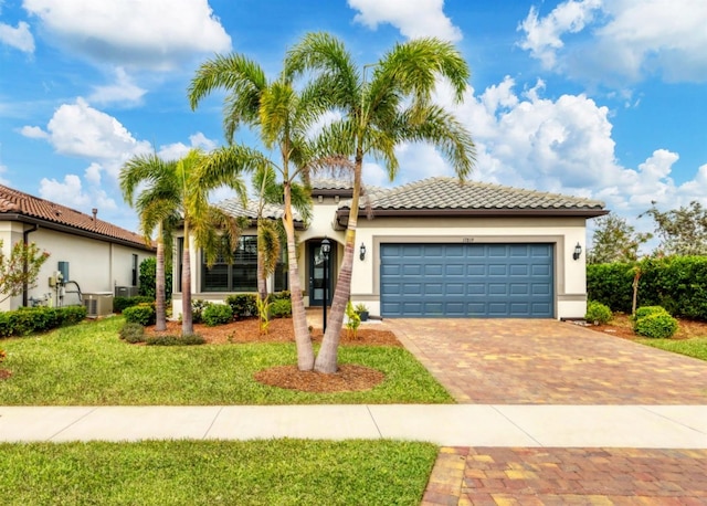 mediterranean / spanish house with a front yard, a garage, and central AC unit