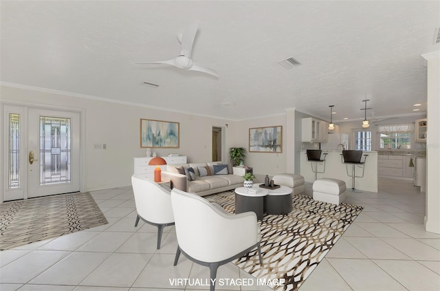 tiled living room with crown molding, a textured ceiling, and ceiling fan