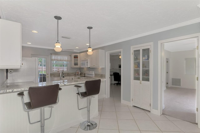 kitchen with white cabinetry, a kitchen breakfast bar, light tile patterned floors, light stone countertops, and white appliances