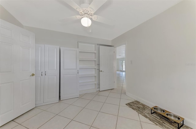 unfurnished bedroom with light tile patterned floors, ceiling fan, and a closet