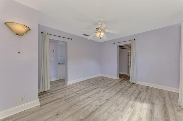 spare room featuring light hardwood / wood-style floors, a barn door, and ceiling fan