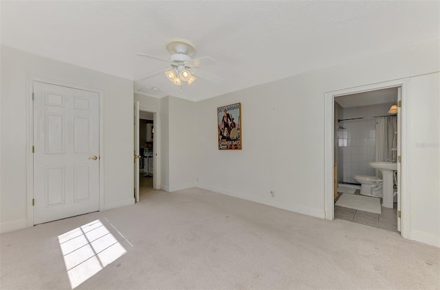 unfurnished bedroom featuring ceiling fan, ensuite bathroom, and light carpet