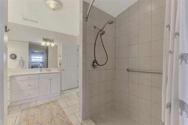 bathroom featuring tiled shower, vanity, toilet, and tile patterned flooring