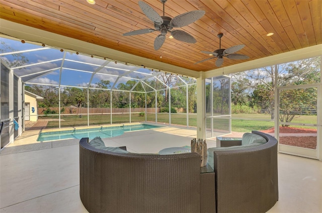 exterior space with ceiling fan, glass enclosure, a patio, and a lawn