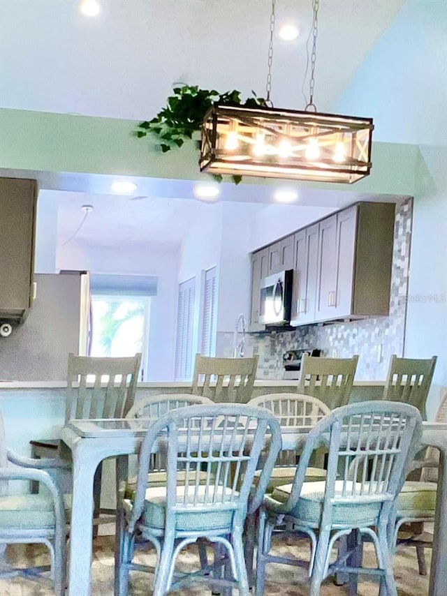 kitchen featuring gray cabinetry, decorative backsplash, and a notable chandelier