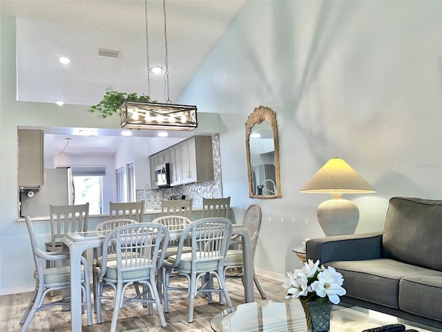 dining space with a chandelier, light hardwood / wood-style flooring, and vaulted ceiling
