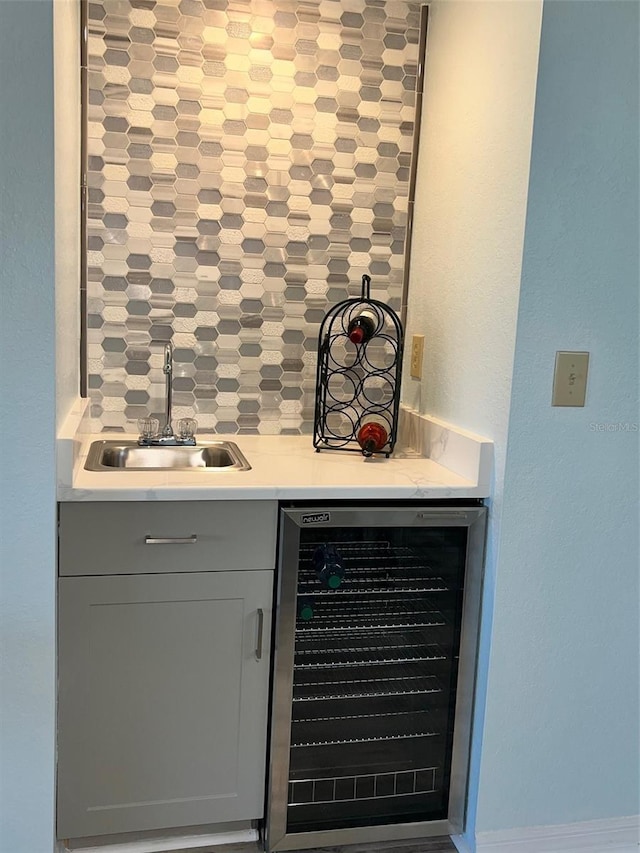 bar featuring wine cooler, gray cabinetry, and sink