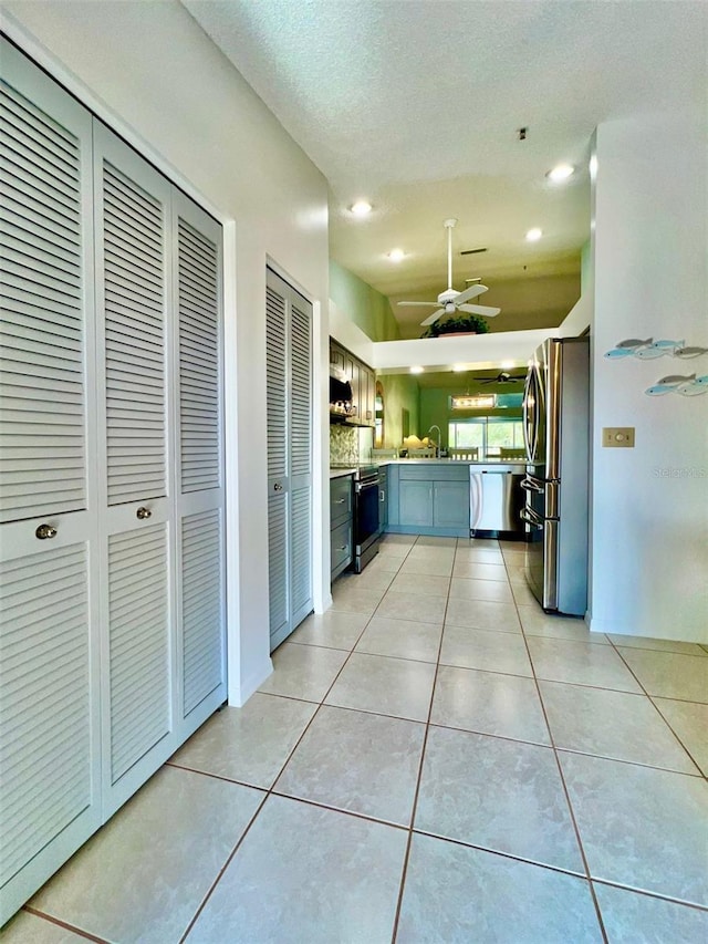 kitchen with appliances with stainless steel finishes, a textured ceiling, ceiling fan, sink, and light tile patterned flooring