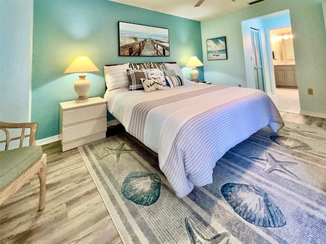 bedroom with connected bathroom, light hardwood / wood-style floors, and ceiling fan
