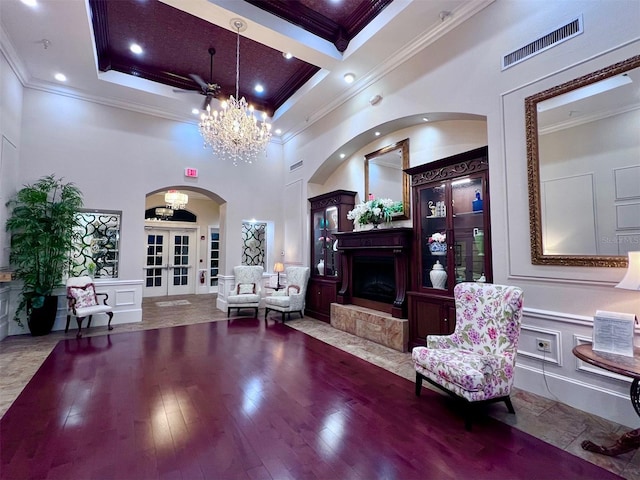sitting room featuring a notable chandelier, ornamental molding, a high ceiling, and french doors