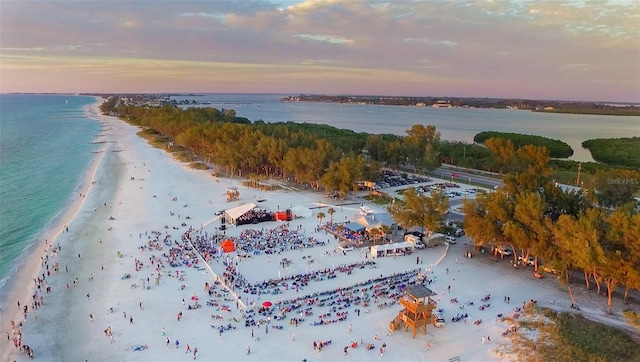 aerial view at dusk with a water view and a beach view