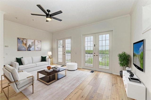 living room with ceiling fan, ornamental molding, light wood-type flooring, and french doors