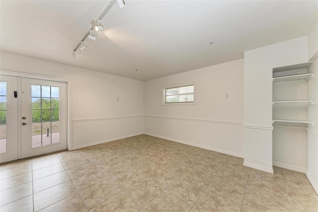 tiled spare room with rail lighting and a textured ceiling