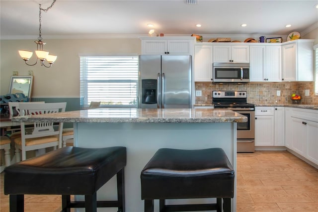 kitchen with pendant lighting, white cabinetry, appliances with stainless steel finishes, and a chandelier