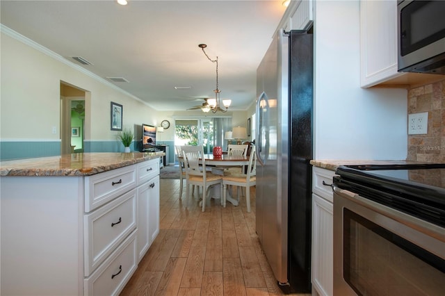 kitchen with appliances with stainless steel finishes, light hardwood / wood-style flooring, white cabinetry, and a notable chandelier