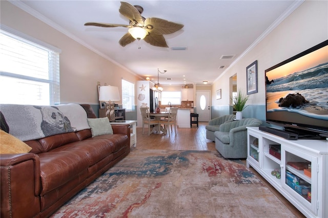 living room with hardwood / wood-style flooring, ceiling fan with notable chandelier, and crown molding