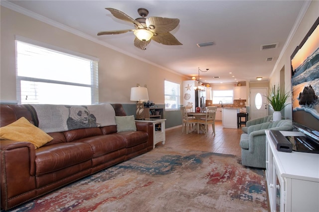 living room featuring hardwood / wood-style flooring, ceiling fan with notable chandelier, and ornamental molding