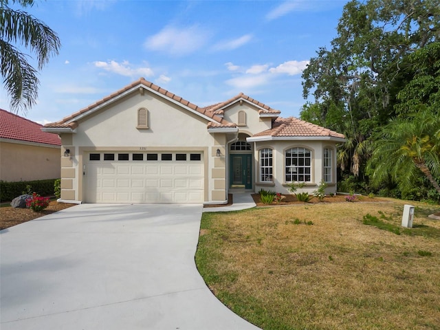 mediterranean / spanish home with a front lawn and a garage