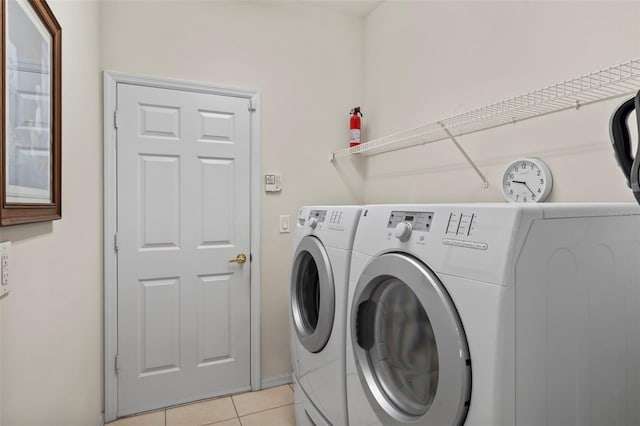 laundry area with independent washer and dryer and light tile patterned floors