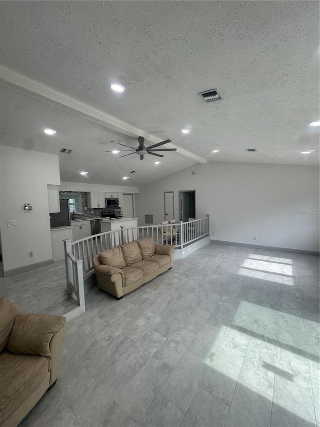 living room with vaulted ceiling with beams, ceiling fan, and a textured ceiling