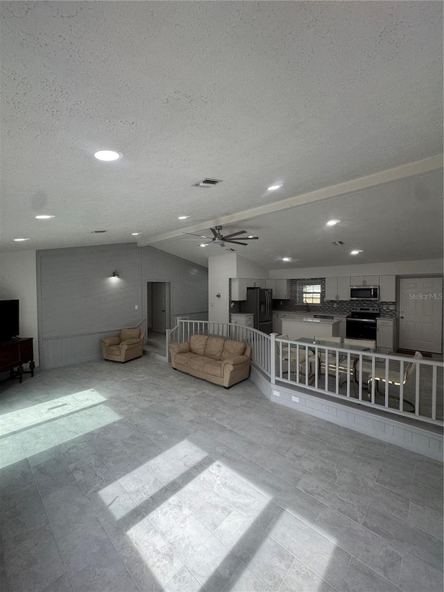 unfurnished living room featuring ceiling fan, a textured ceiling, and vaulted ceiling