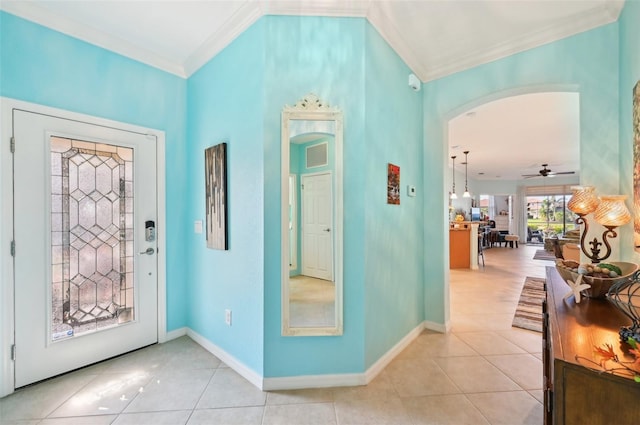 tiled foyer with ceiling fan and crown molding