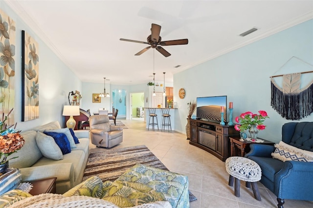 tiled living room featuring ceiling fan with notable chandelier and ornamental molding