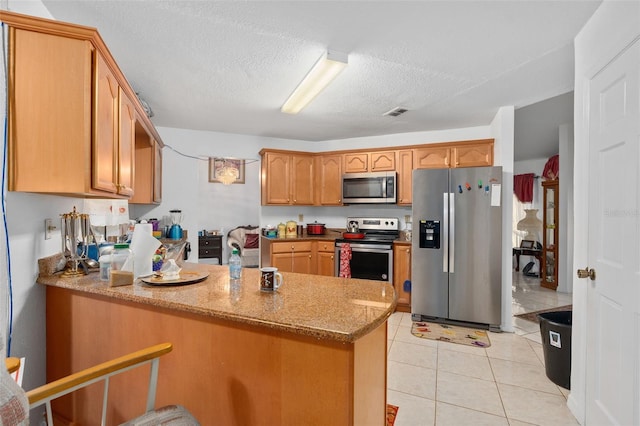 kitchen featuring kitchen peninsula, appliances with stainless steel finishes, light tile patterned floors, and light stone counters