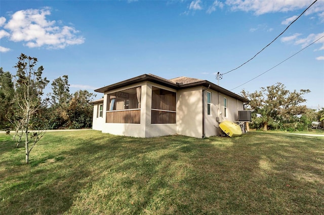 view of side of property featuring a sunroom, cooling unit, and a yard