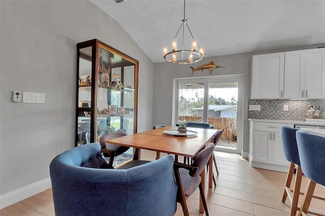 dining room featuring light hardwood / wood-style flooring, vaulted ceiling, and a notable chandelier