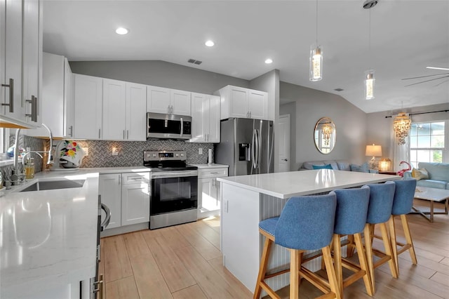 kitchen with white cabinets, lofted ceiling, and appliances with stainless steel finishes