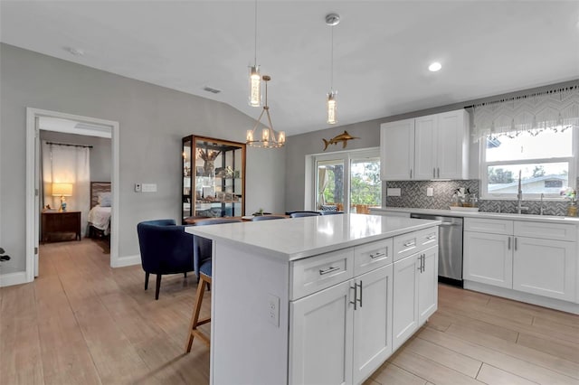 kitchen with sink, dishwasher, a kitchen island, pendant lighting, and white cabinets