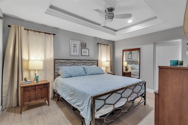 bedroom with ceiling fan, light hardwood / wood-style floors, ornamental molding, and a tray ceiling