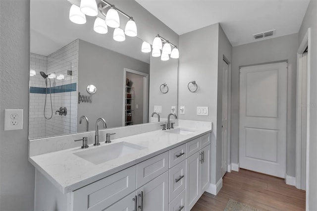 bathroom with a tile shower, hardwood / wood-style floors, and vanity