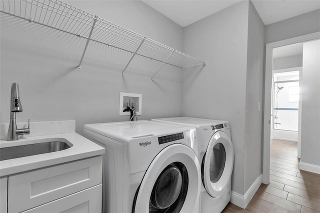 laundry room with washer and clothes dryer, cabinets, and sink