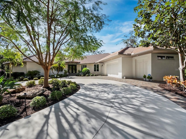 view of front of home with a tiled roof, stucco siding, driveway, and a garage