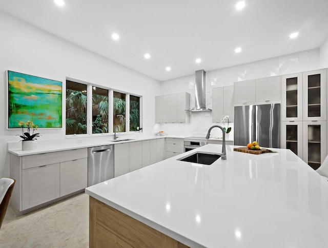 kitchen featuring wall chimney range hood, gray cabinets, stainless steel appliances, and sink