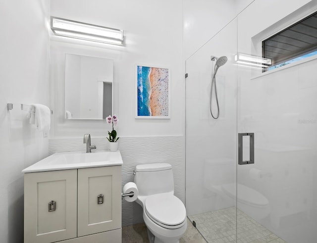 bathroom featuring vanity, a shower with shower door, tile walls, and toilet