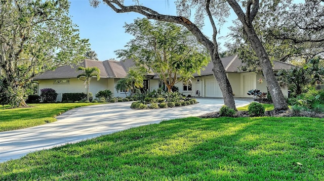 view of front of property featuring stucco siding, a front lawn, an attached garage, and driveway