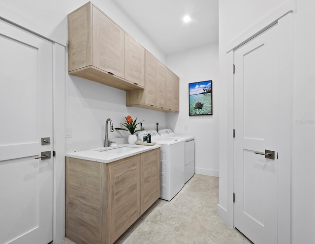 clothes washing area with cabinet space, baseboards, washer and dryer, and a sink