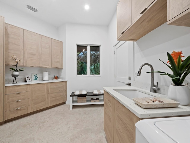 laundry room with cabinet space, a sink, and visible vents