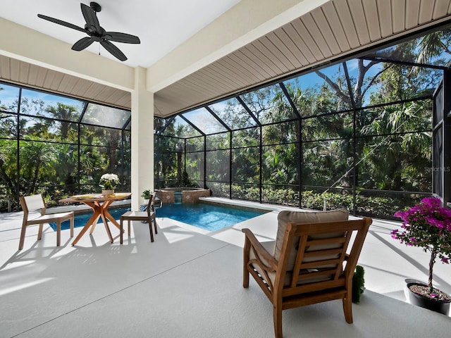 view of swimming pool featuring ceiling fan, glass enclosure, a pool with connected hot tub, and a patio