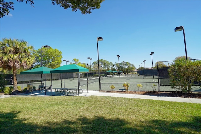 view of tennis court with fence and a yard