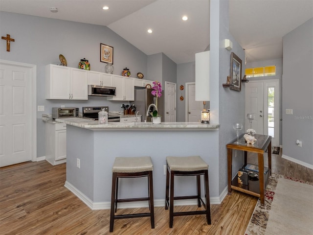 kitchen featuring kitchen peninsula, white cabinets, light hardwood / wood-style flooring, and appliances with stainless steel finishes