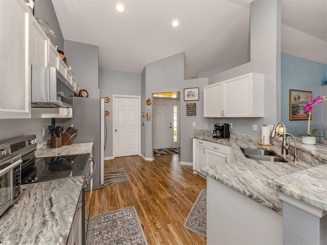 kitchen featuring vaulted ceiling, sink, white cabinetry, light stone counters, and stainless steel appliances