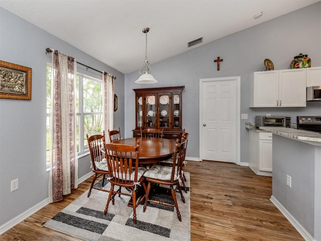 dining space featuring light wood-type flooring and vaulted ceiling