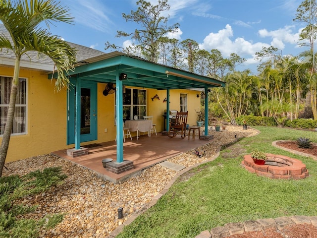 back of house with a fire pit, a lawn, and a patio