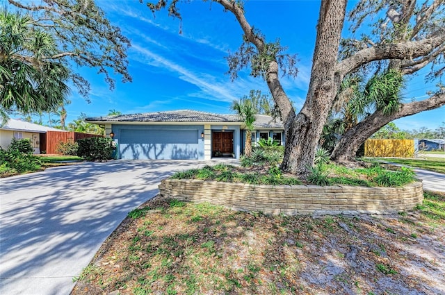 ranch-style house with a garage, a tile roof, fence, and concrete driveway