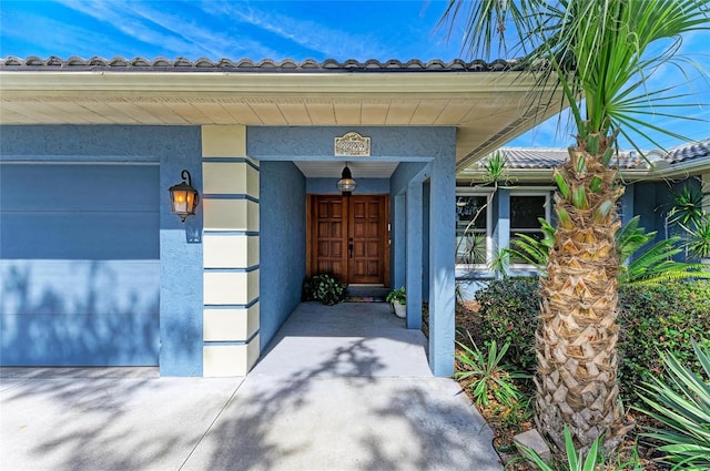 property entrance featuring an attached garage and stucco siding