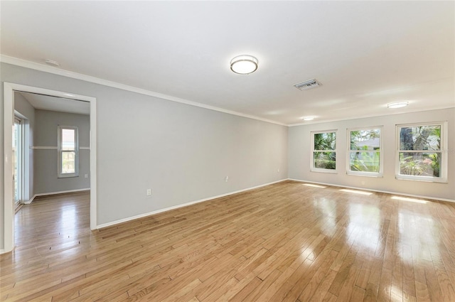 unfurnished room featuring baseboards, visible vents, crown molding, and light wood finished floors